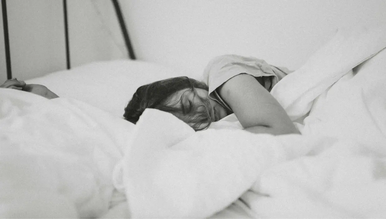 black and white picture of a woman sleeping in bed